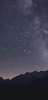 Starry night sky over silhouettes of mountain peaks.