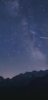 Starry night sky over a mountain range with shooting star.