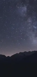 Starry night sky over mountain range in dark blue tones.