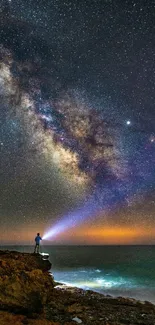 Person stargazing by the ocean under a vivid Milky Way sky.