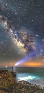 Person on rocks under a starry sky, gazing at Milky Way over the ocean.