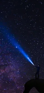 Silhouette with blue beam under starry night sky.