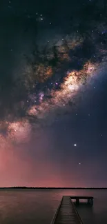 Milky Way over a calm lake and wooden pier at night.