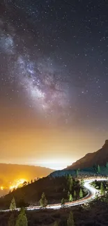 Starry night sky over mountains with city lights below.