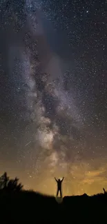 Silhouette under starry night sky with Milky Way in view.