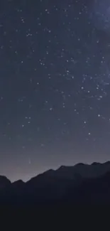 Mobile wallpaper featuring a starry night sky above mountains.