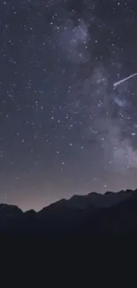 Dark starry night sky with shooting star over mountains.