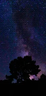 Starry night sky with a silhouetted tree in the foreground under cosmic display.