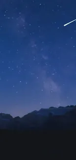 Starry night sky with mountain silhouette and shooting star.