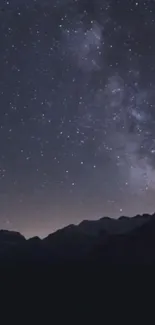 Starry night sky over dark mountains.