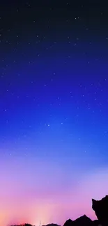 Starry night sky with blue gradient and silhouette of rocks.