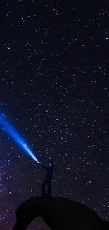 Silhouette of person with flashlight against a starry night sky on a rocky arch.