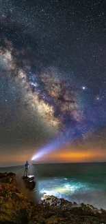 Starry night sky over ocean with person shining light.