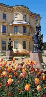 Stately home with vibrant flower garden and sculptures.