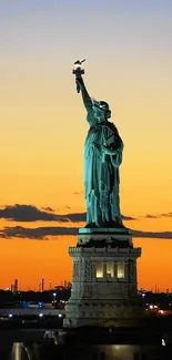 Statue of Liberty at sunset with a vibrant orange sky.