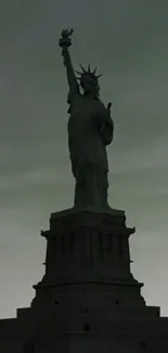 Silhouette of the Statue of Liberty against a dark sky.