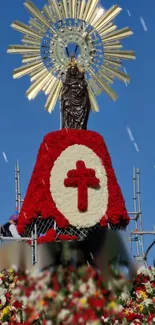 Floral statue arrangement with red flowers and blue sky backdrop.