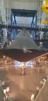Stealth jet displayed in a modern hangar with dramatic lighting.