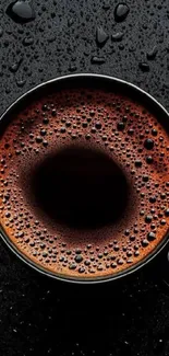 Steaming cup of coffee with rich foam texture on a dark background.