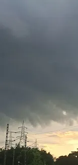 Dark stormy sky with electric pylons silhouetted against a sunset.