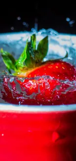 Dynamic splash of a strawberry in a red mug filled with water.