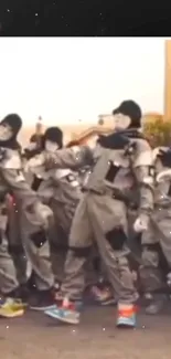 Masked dancers in gray costumes perform energetically on an urban street.