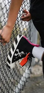 Sneaker against a chain-link fence showcasing street fashion.