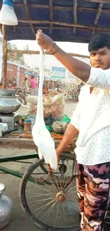 Street vendor holding a bird in a vibrant market scene.