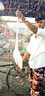 Street vendor holds up a white chicken in a bustling outdoor market.