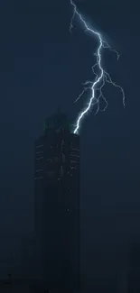 Lightning strikes a skyscraper in a dark cityscape at night.