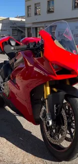 Vibrant red motorcycle parked on a city street under the sun.