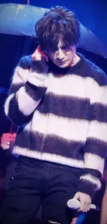 Person in striped sweater with black and white theme on stage with cool lighting effects.