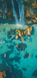 Aerial view of kayakers by turquoise beach waterfall.