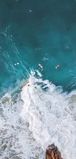 Aerial view of ocean waves and surfers at a scenic beach.