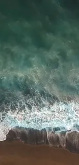 A breathtaking aerial view of ocean waves crashing on a sandy beach.