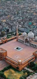 Aerial view of a historic mosque with domes amidst a bustling cityscape.