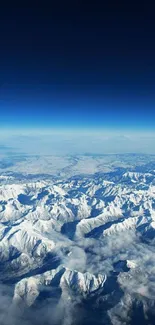 Aerial view of snow-capped mountains under a deep blue sky, captured from above.