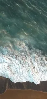 Aerial view of ocean waves crashing on a sandy beach with teal blue water.