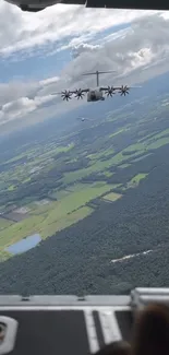 Military aircraft over vibrant green landscape from aerial view.