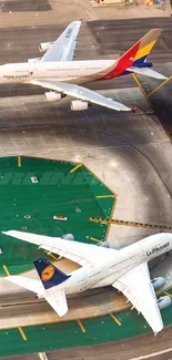 Aerial view of two commercial airplanes on a spacious airport runway.