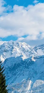 Snow-covered alps under a clear blue sky with clouds.