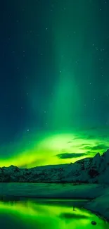 Vibrant green aurora borealis over snowy mountains and a reflective lake at night.