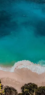 Aerial view of a turquoise beach with golden sand and blue ocean waves.