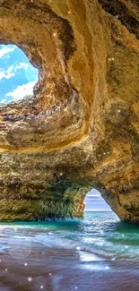 Beautiful cave with ocean and blue sky views on a sandy beach.