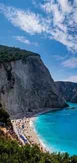 Breathtaking view of a beach with turquoise waters and imposing cliffs under a blue sky.