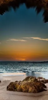 Sunset over ocean from sandy beach cave view.