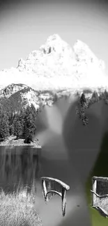 Black and white mountain scene with chairs by a lake.