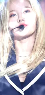 Blonde woman singing on stage with vibrant lights and microphone.