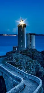 Lighthouse illuminated at night with ocean backdrop.