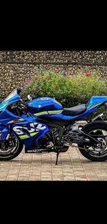 Blue motorcycle parked against stone wall backdrop.